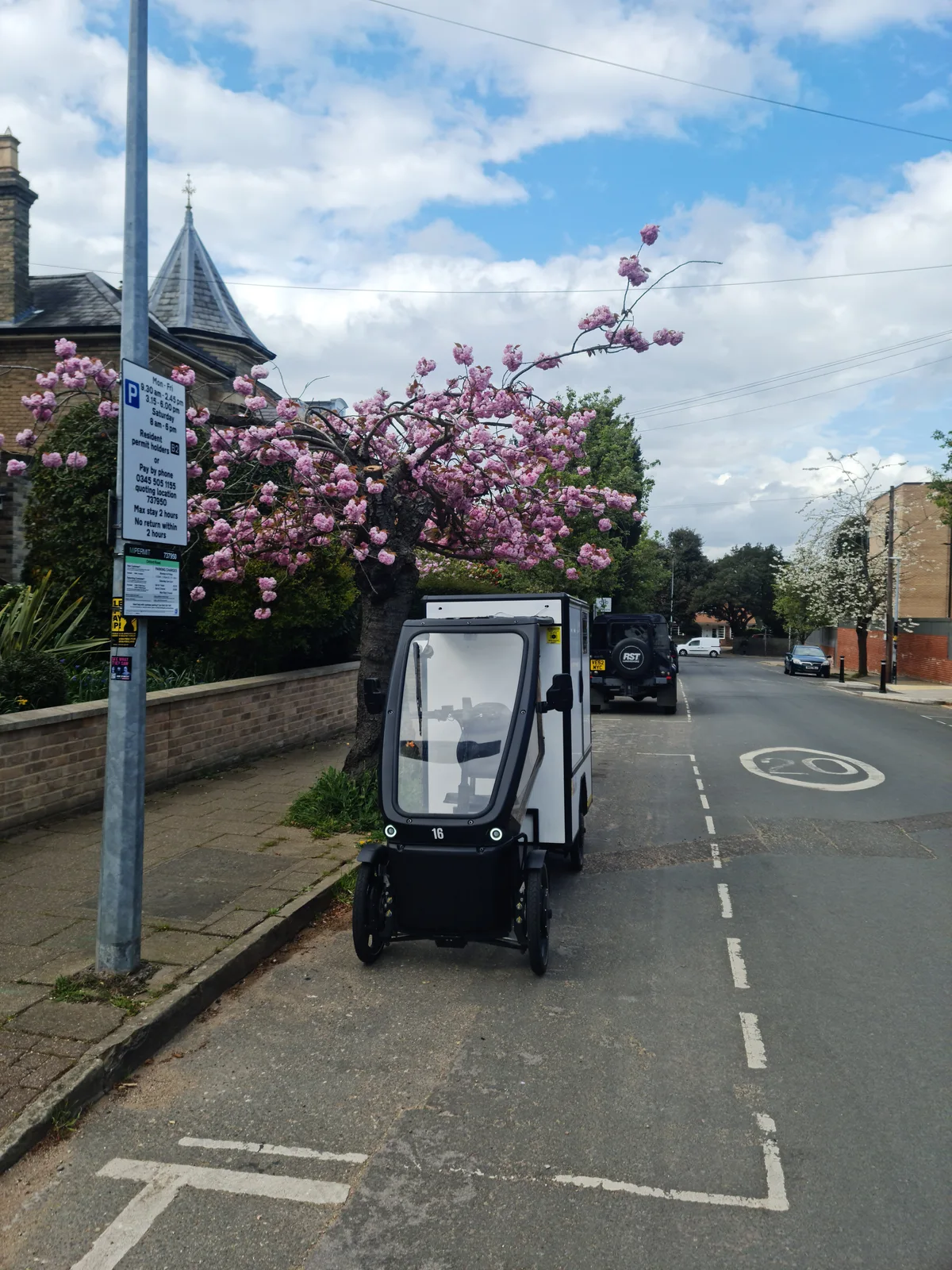 SendSimply electric cargo bike on a residential street under spring blossom in Colchester
